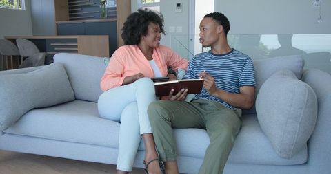 Couple Relaxing and Conversing on Sofa with Book