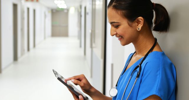 Smiling Nurse Using Tablet in Hospital Hallway - Download Free Stock Images Pikwizard.com
