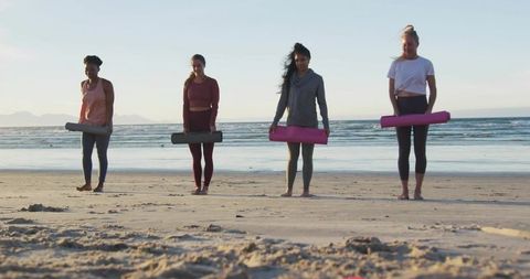 Women Holding Yoga Mats Stand on Beach at Dawn