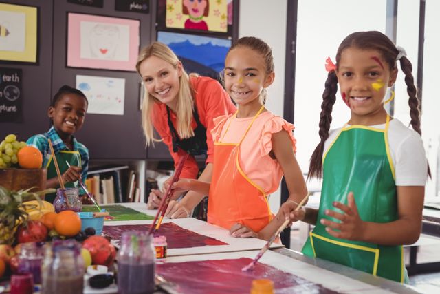 Portrait of smiling teacher and schoolkids standing in drawing classroom