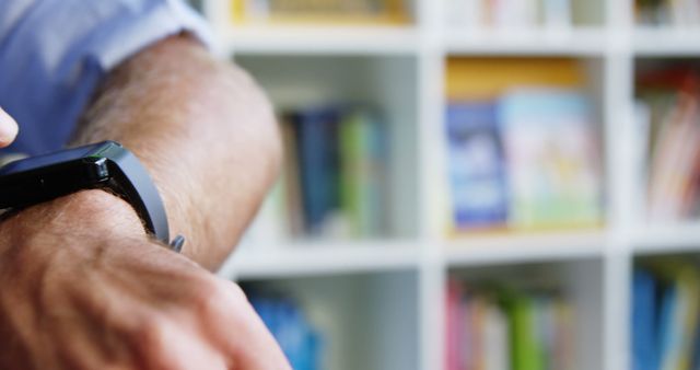 Man Checking Smartwatch Against Bookshelves Background - Download Free Stock Images Pikwizard.com