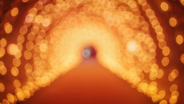 Golden bokeh light tunnel creating warm festive archway with soft blue focal point