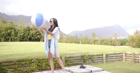Joyful woman playing with beach ball in sunny garden