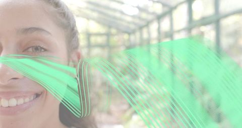 Smiling woman showing teeth in glasshouse with mint green flowing ribbon overlay and bokeh