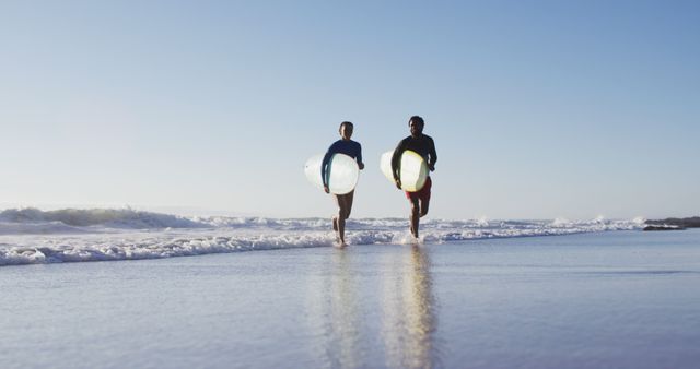 African american couple running with surfboards on the beach. holiday and healthy outdoor leisure time by the sea.