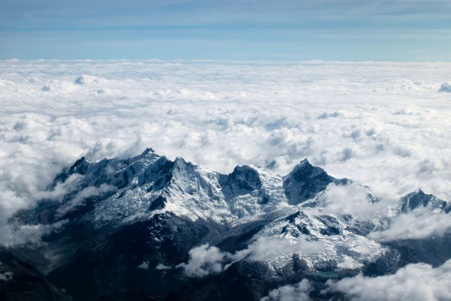 Aerial View of Majestic Snow-Capped Mountains Surrounded by Clouds - Download Free Stock Photos Pikwizard.com