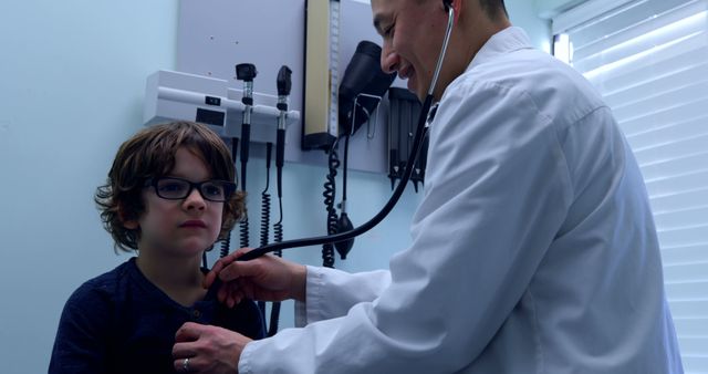 Doctor conducting a health examination on a young boy using a stethoscope in a clinical setting. Applicable for use in healthcare articles, medical promotions, pediatric resources, and health education materials.