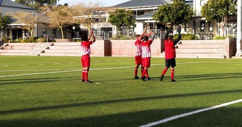 Soccer Team Celebrating Goal with Raised Arms on Field