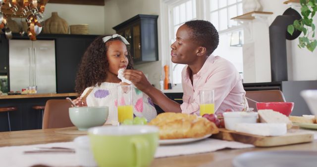 Mother Feeding Daughter at Breakfast Table in Modern Kitchen - Download Free Stock Images Pikwizard.com