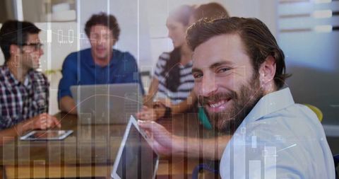 Smiling bearded man presenting digital analytics to team during collaborative office meeting