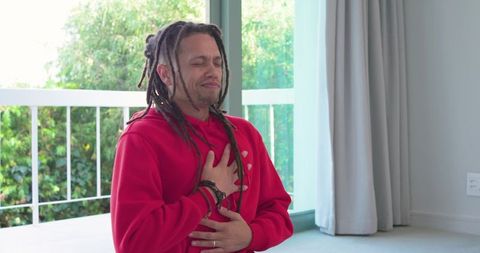 Mid-adult african american man clutching chest near balcony door expressing chest pain