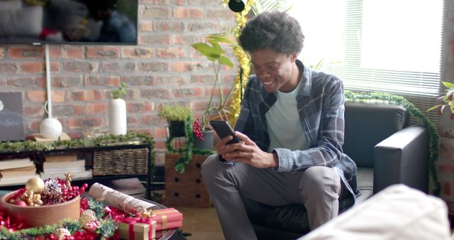 Young Man Enjoying Christmas Cheer While Using Smartphone at Home - Download Free Stock Images Pikwizard.com