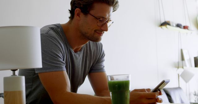 Casual Man Texting While Enjoying Green Smoothie at Home - Download Free Stock Images Pikwizard.com