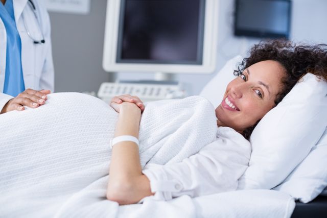 Portrait of pregnant woman smiling during ultrasound scan in hospital