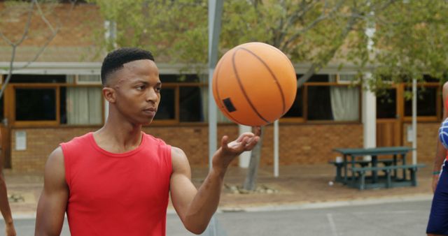 Basketball player spinning ball on finger in basketball court outdoors