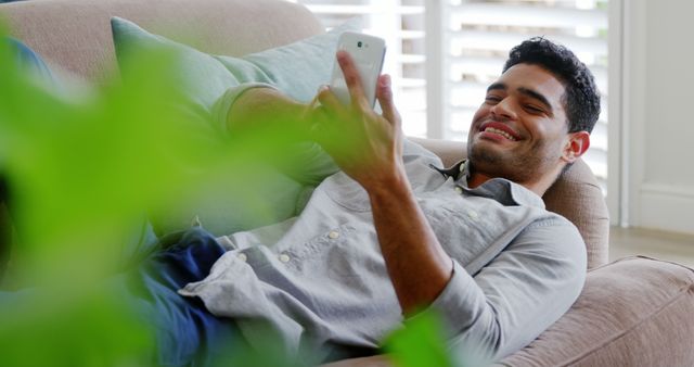 Young Man Relaxing on Couch and Looking at Smartphone - Download Free Stock Images Pikwizard.com