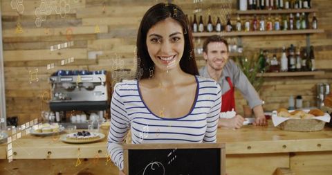 Smiling Cafe Worker Holding Blank Chalkboard in Rustic Coffee Shop