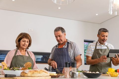 Middle-aged friends cooking together in modern kitchen