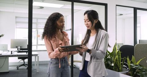 Diverse coworkers engaged with tablet in modern office