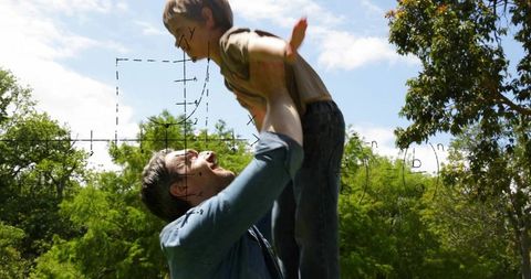 Father lifting son high in sunlit park playing outdoors joyful family bonding moment