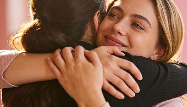 Sharing warm embrace between friends smiling with comfort connection trust and affection