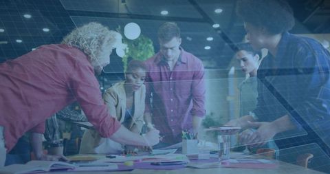 Creative team collaborating around coworking table with colorful sticky notes and project plans