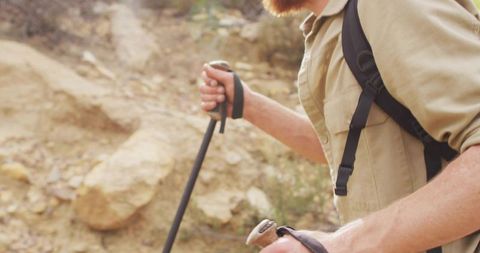 Man Hiking with Trekking Poles on Rocky Terrain in Wilderness