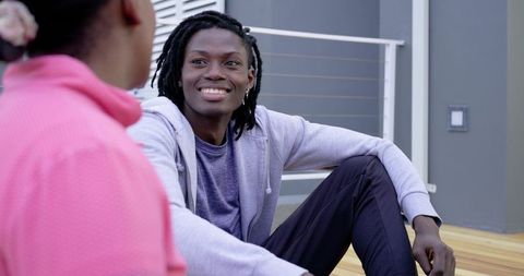 African American couple chatting on balcony deck, man sitting relaxed in hoodie