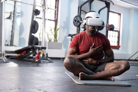 African american man meditating with vr headset and smartwatch in gym for virtual mindfulness
