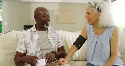 Senior couple using home blood pressure monitor for health management