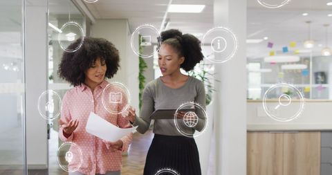 Diverse Businesswomen Discussing Work in Modern Office with Digital Icons