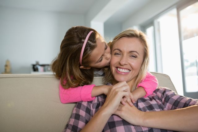 Mother and daughter sharing a tender moment in the living room. Perfect for use in family-oriented advertisements, parenting blogs, and articles about family relationships and home life.