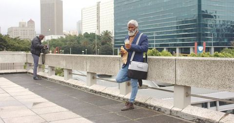 Mature African American Professional Standing on Urban Overpass with Coffee and Pastry