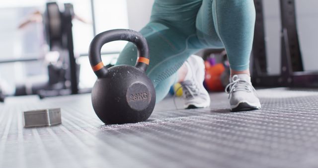 Focused athlete in gym training with 28 KG kettlebell. Perfect for fitness instructors, gym promotions, exercise equipment ads, and workout routines.