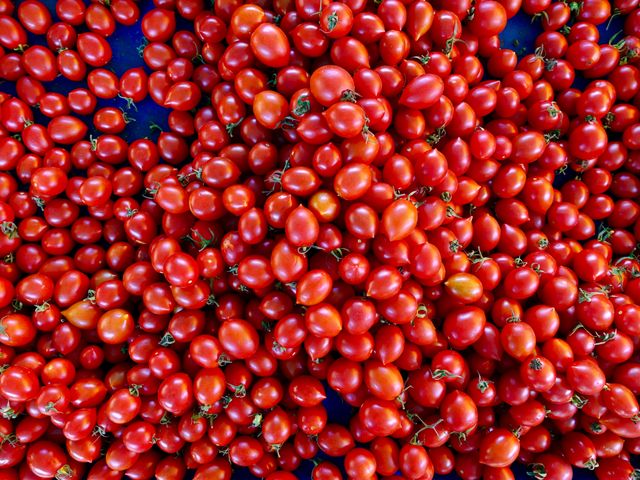 An overhead view of a large quantity of fresh red cherry tomatoes. The vibrant color and abundance make it perfect for a food blog, grocery store advertisement, or nutrition-related content. Ideal for themes related to healthy eating, organic farming, or vegetables.