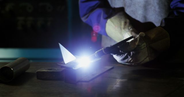 Welder wearing safety gear using torch to weld metal with intense light. Suitable for industrial themes, engineering, metalworking concepts, training materials, and workshop-related content.