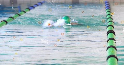 Competitive swimmer powering through lane with green cap, water splash and analytics overlay