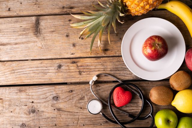 Stethoscope with heart shape and various fresh fruits on wooden table. Ideal for promoting healthy eating, organic food, and wellness. Suitable for use in healthcare, nutrition, and diet-related content.