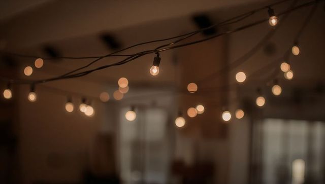 Glowing Hanging String Lights Casting Amber Bokeh Across Cozy Dim Living Room