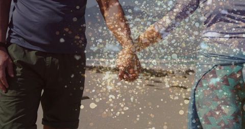 Mature couple hand in hand on beach with sparkling lights
