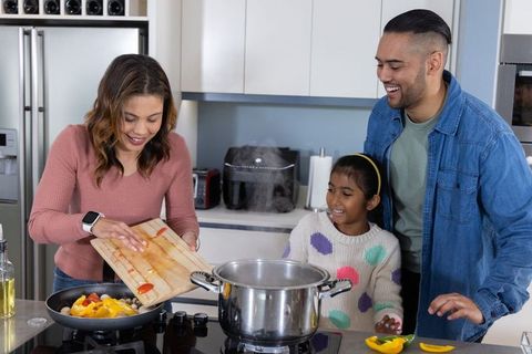 Family cooking together on kitchen island parents and daughter preparing healthy dinner