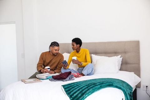 Couple Relaxing on Bed with Coffee and Smartphone Interaction