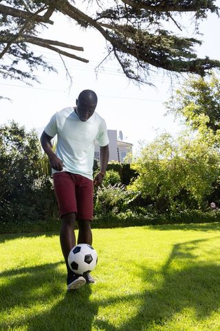 Man Dribbling Soccer Ball in Backyard Lawn