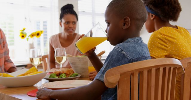 Front view of black family eating food on dining table in a comfortable home. Boy drinking glass of juice 4k