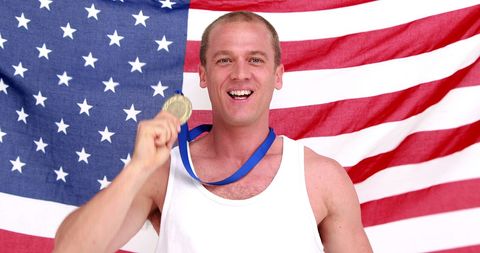 Joyful Athlete Holding Gold Medal in Front of USA Flag