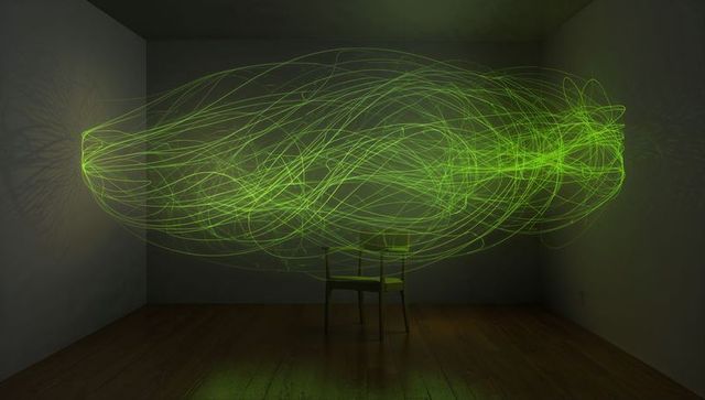 Floating emerald light sculpture surrounding chair with glowing neon loops and reflections