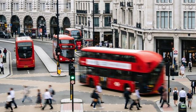 Red double-decker bus blurring through busy london junction with commuters and pedestrians