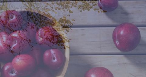 Red plums in wooden bowl on outdoor patio table