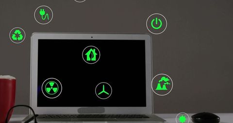 Minimalist laptop displaying green renewable energy icons on black screen for eco tech