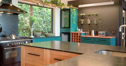 Sunlit Modern Rustic Kitchen with Central Island, Teal Cabinets and Dark Stone Countertop